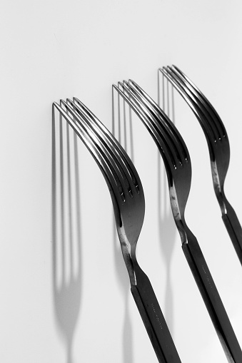 three metal forks placed vertically casting a shadow