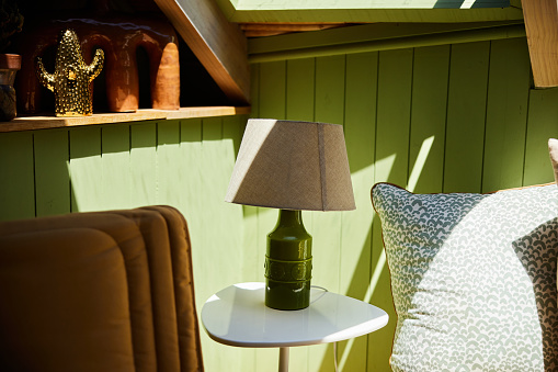 Lamp sitting on a side table in the comfortable living area of a rustic holiday home with green wood-paneled walls