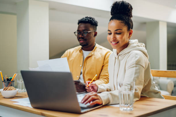 istock Diverse couple using laptop while sitting at the table at home 1466359147