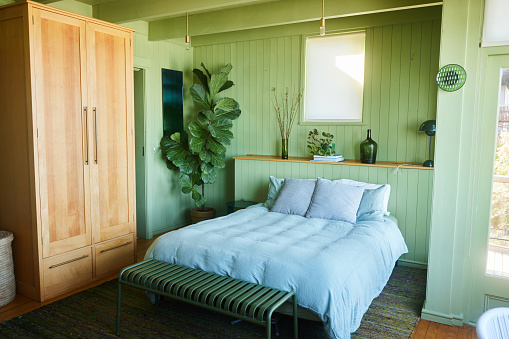 Comfortable bed in a bedroom with green wood-paneled walls in a rustic vacation home