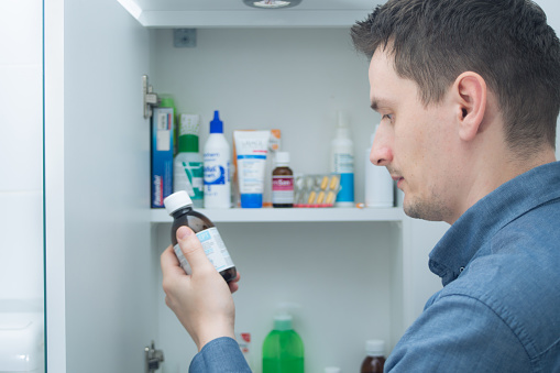 Man looking at bottles from medicine cabinet