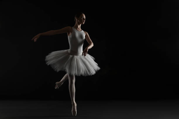 istock Young ballerina practicing dance moves on black background. Space for text 1466362951