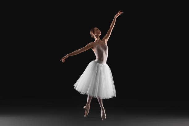 istock Young ballerina practicing dance moves on black background 1466362964