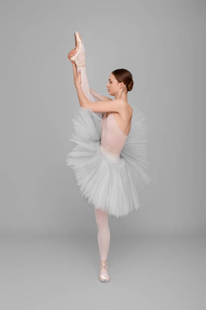 istock Young ballerina practicing dance moves on light grey background 1466363096