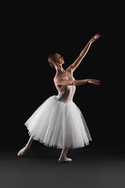 istock Young ballerina practicing dance moves on black background 1466363111