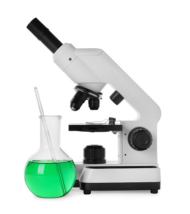 Laboratory flask with green liquid and microscope isolated on white