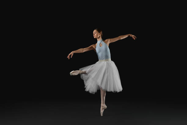 istock Young ballerina practicing dance moves on black background 1466363180