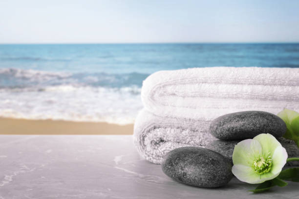 istock Towels, spa stones and flower on marble table against seascape, space for text 1466363420