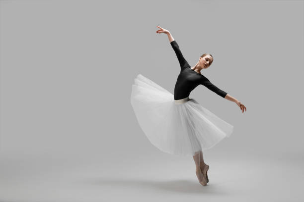istock Young ballerina practicing dance moves on light grey background. Space for text 1466363534