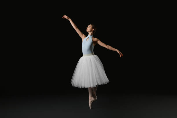 istock Young ballerina practicing dance moves on black background 1466363536