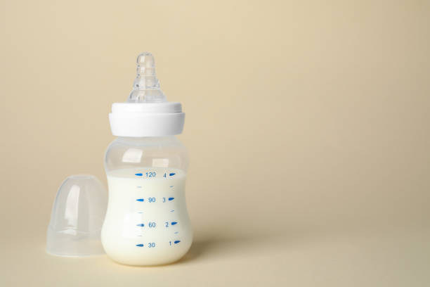 istock Feeding bottle with infant formula on beige background. Space for text 1466363710