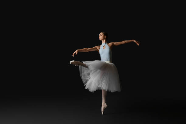 istock Young ballerina practicing dance moves on black background. Space for text 1466363747