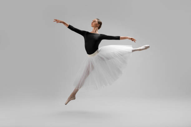 istock Young ballerina practicing dance moves on light grey background 1466363899