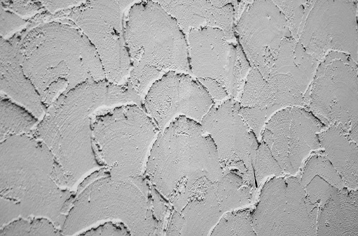 Texture of decorative plaster. The background of plaster roughly applied to the wall in the form of semicircles. Gray strokes on the wal