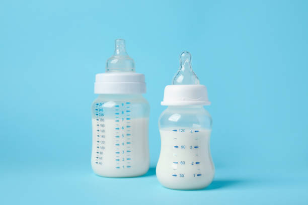 istock Feeding bottles with milk on light blue background 1466364199