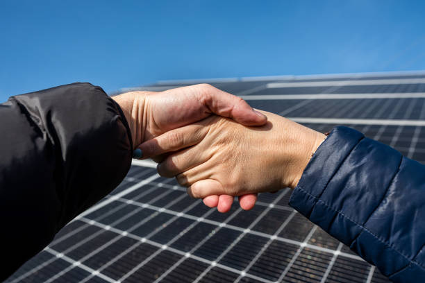 istock Two people shaking hands against a solar panel after signing a renewable energy deal. 1466365515
