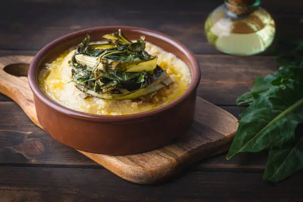 Pugliese recipe   Fave e cicoria:  fava beans or broad beans porridge  with Asparagus chicory, italian dandelion chicory or Catalonian chicory on the wooden  rustic table, tradition poor Bari cuisine