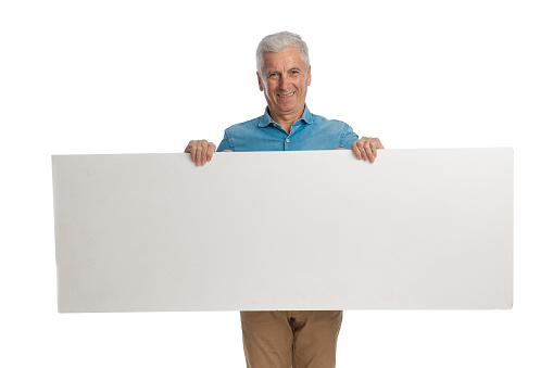 picture of proud grandpa holding and presenting board while smiling in front of white background in studio