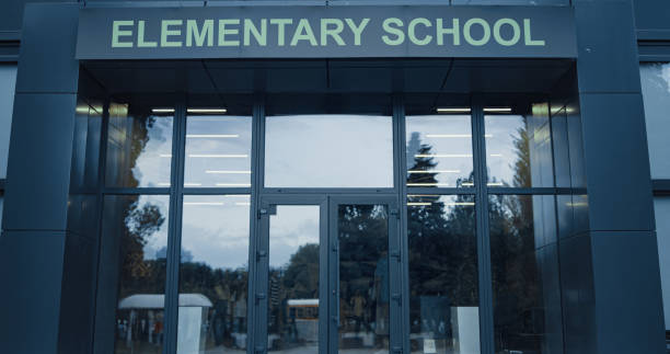 istock Elementary school exterior outside with closed door. Window reflecting sky trees 1466375932