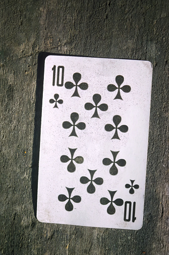 Playing card ten of cross on the background of an old wooden table close-up.