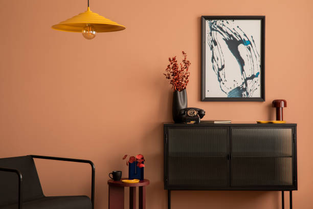 istock Creative composition of living room interior with mock up poster frame, glass sideboard, black armchair, round coffee table, vase with dried flowers and personal accessories. Home decor. Template. 1466380476