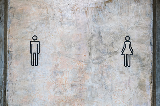 Male and female icon sign in front of the toilet, gender symbol on concrete wall