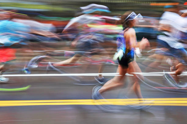 Blurred Action Of Marathon Runners On City Street The blurred motion of a group of marathon runners as they run on an urban street. Everyone is unrecognizable by the blur of the motion. marathon stock pictures, royalty-free photos & images