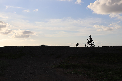 Silhouette of cyclist with racing bicycle on the road in black and white with very dark tones