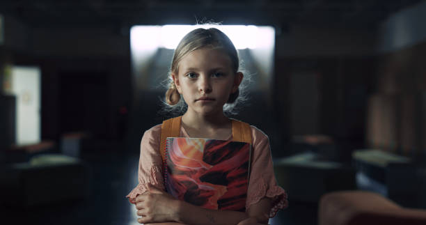 Portrait upset frightened schoolgirl standing hallway alone. Lonely girl posing Portrait of upset frightened schoolgirl standing dark hallway alone. Lonely depressed elementary age girl posing in school corridor with books. Helpless blonde child full of despair looking camera. child sadness stock pictures, royalty-free photos & images