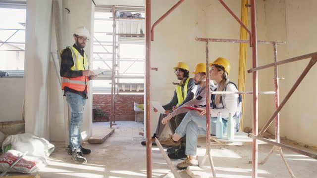 Three students of a trade school are listening to a construction worker in a worksite