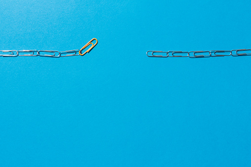 Chains formed by clips in which an orange link serves as a link. Mediator concept. Blue background.
