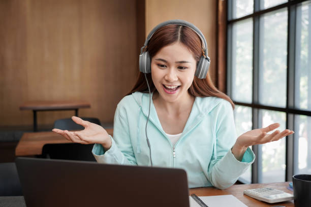 istock Female student wearing headphone and using laptop to asking question with teacher on video conference 1466392418