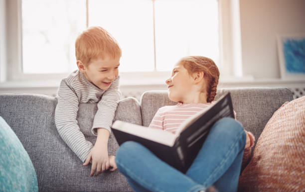 istock Cute children sitting on the soft sofa and reading books 1466393449
