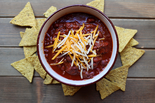 A bowl of homemade chili on a wooden table