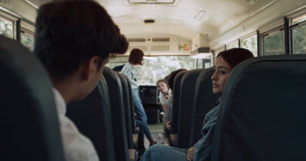 istock High school students sitting communicating in schoolbus. Pupils waving friend. 1466395687