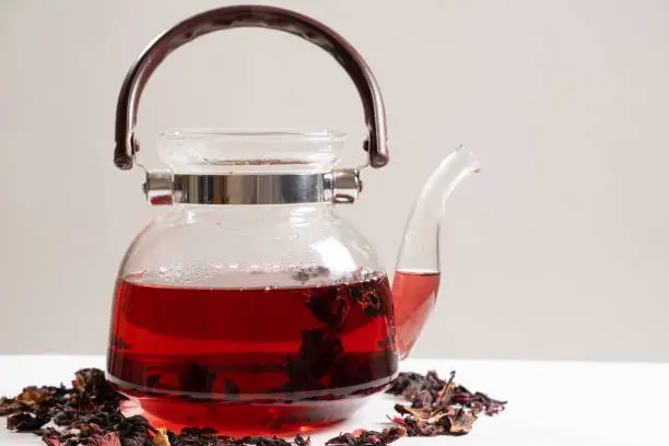 Red hibiscus tea from the petals of a Sudanese rose in a glass teapot, copy the place for the text.
