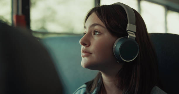 Girl teenager traveling bus with headphones close up. Brunette listening music. Thoughtful girl teenager traveling bus alone with headphones close up. Cute brunette student listening music with headset looking window. Pretty schoolgirl passenger enjoying daily ride to school. slow motion face stock pictures, royalty-free photos & images