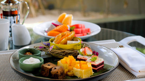 istock Tropical desserts, cakes, and fruits on a table set with plates. 1466400140