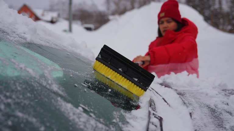 Woman cleaning the snow from a car