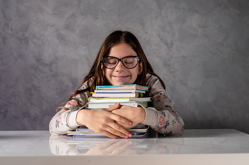 portrait of a happy little girl hugging books