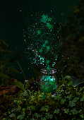 istock Green star shape glittering confetti firework from small glass bottle in green moss with shamrock. 17 March St Patrick's Day magical concept 1466404190