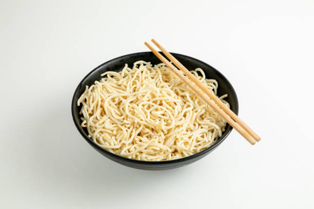 istock yellow noodle in a black bowl isolated on white background 1466405804