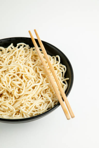 istock yellow noodle in a black bowl isolated on white background 1466405815