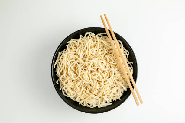 istock yellow noodle in a black bowl isolated on white background 1466405849