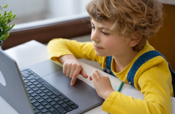 istock Close-up of child hands typing on the keyboard laptop using touchscreen. Distance learning online education. Schoolboy girl studying at home with digital tablet notebook and doing school homework. Side view 1466406743