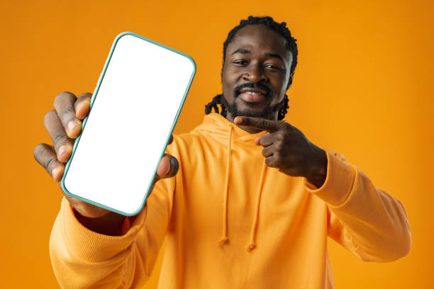 istock Smiling african man pointing at cellphone with blank screen with copy space 1466407670
