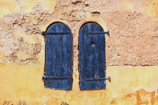 istock building yellow old wall windows closed with black wooden shutters. 1466408901