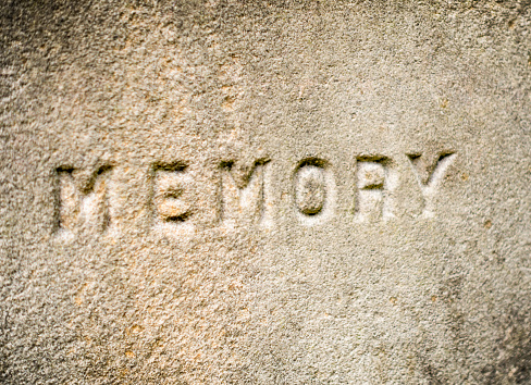 The word 'memory' carved in stone, photographed with a shallow depth of field.