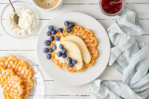 Waffles, blueberries and pear with cottage cheese on a wooden table