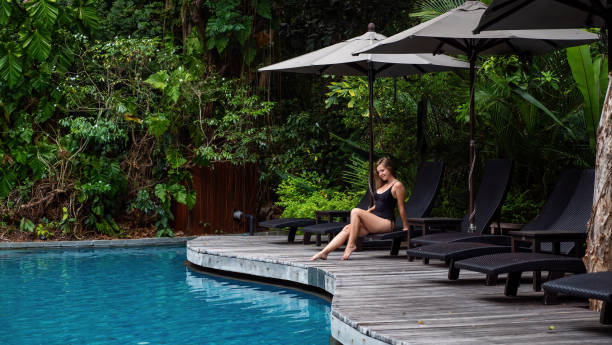istock Tan young model in black bikini, posing and relaxing by swimming pool 1466423481